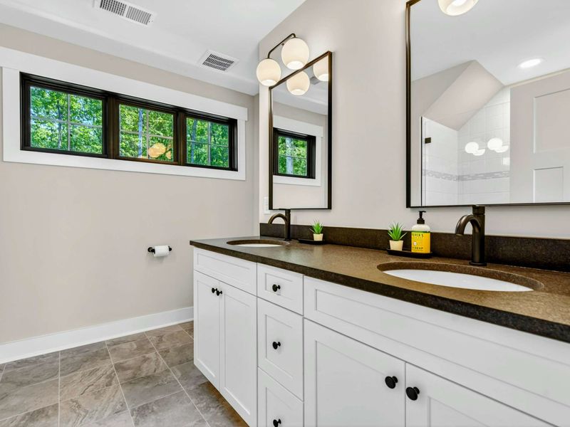 Bathroom 3 - Double vanity with dark stone counter, globe sconces, and a transom window for natural light.