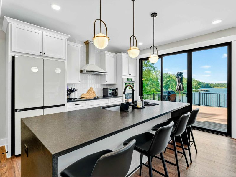 Kitchen - The island's waterfall edge and bar seating face the sliding glass door with lake views beyond.