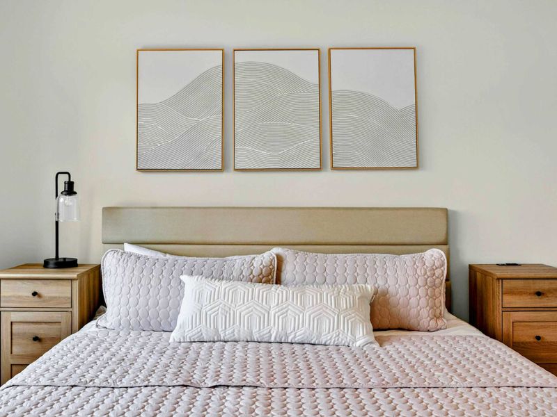 Bedroom 4 - Close-up of the king bed with wave art triptych and warm oak nightstands.