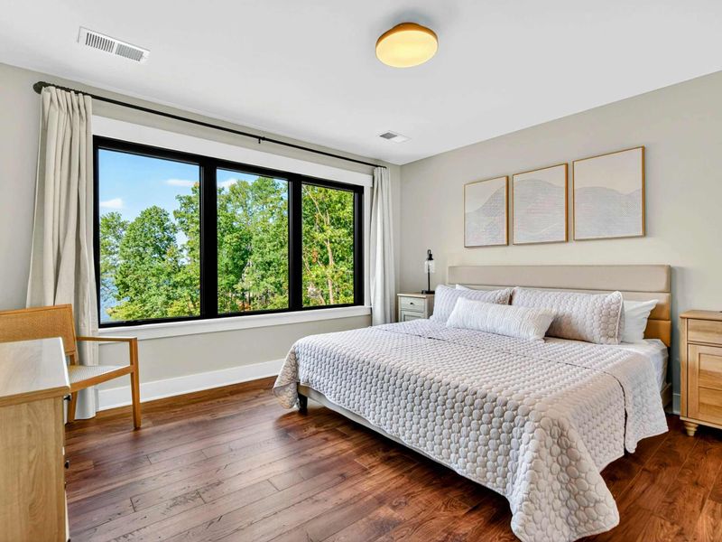 Bedroom 4 - King bed with abstract art diptych, desk area, and lake views through large windows.