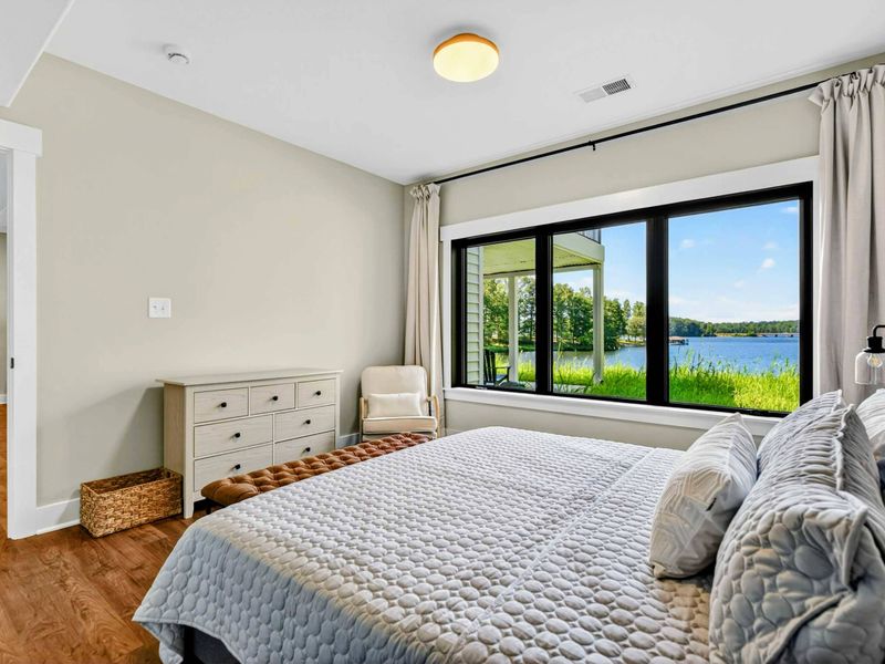 Bedroom 5 - King bed on the lake level with a window showcasing the lake, patio, and dock beyond.