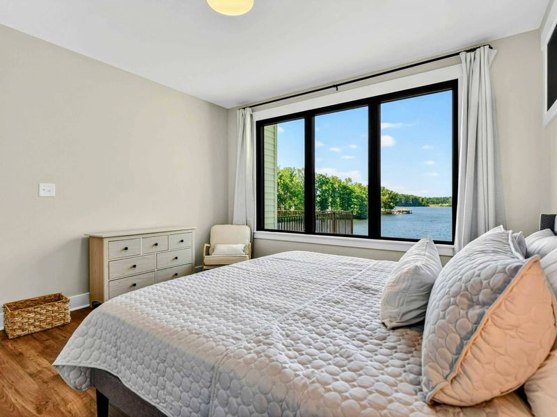 Primary Suite - Lake level king suite with picture window framing the waterfront and patio beyond.