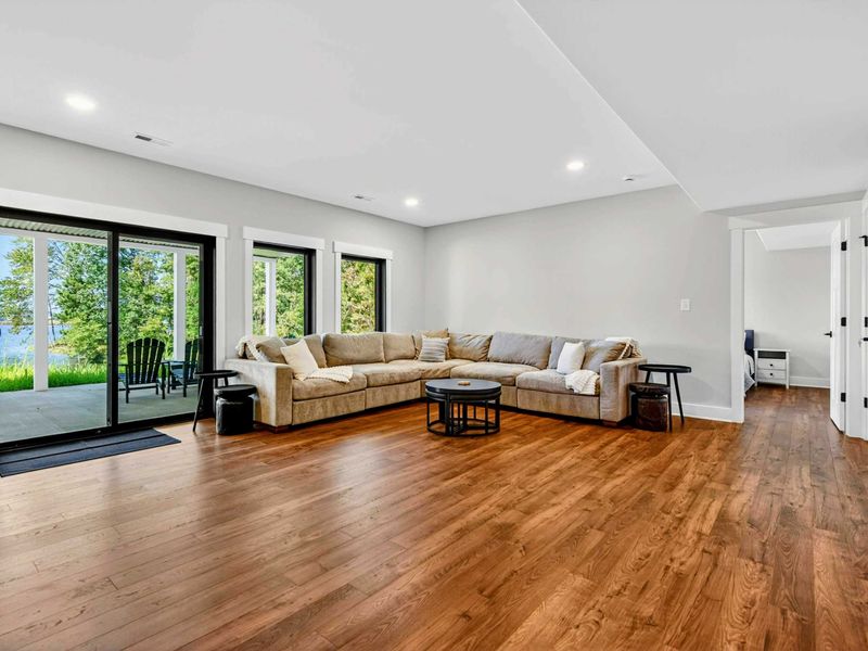 Lower Level Family Room - Sectional arranged for movie nights with the lake visible through the glass doors.