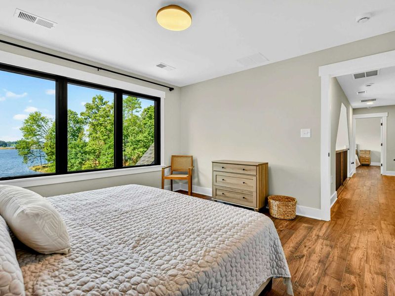 Bedroom 2 - Spacious room with lake views, hallway to the ensuite, and warm hardwood floors.