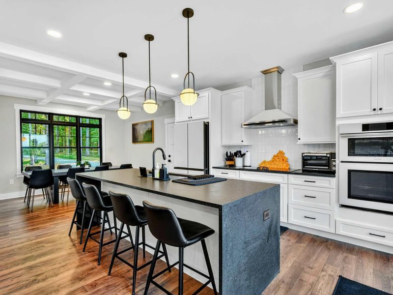 Kitchen - White cabinetry, stainless hood, double wall ovens, and globe pendants over the generous island.
