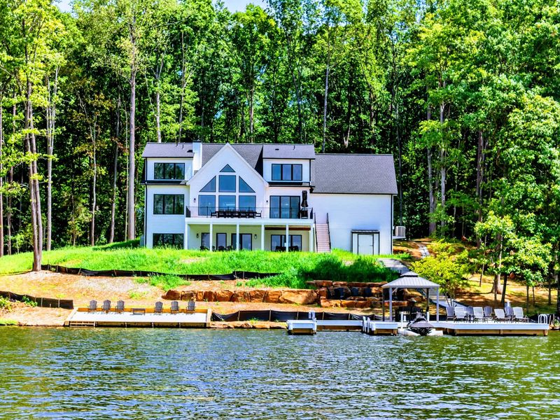 Waterfront - The home's A-frame windows and expansive deck face the lake from a gentle rise.