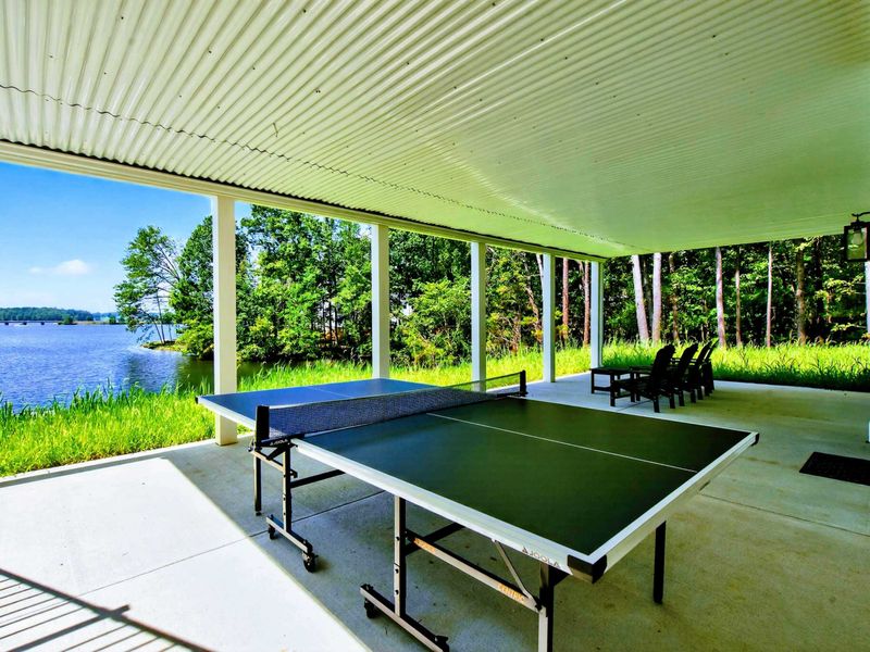 Covered Patio - Wider view showing the ping pong table and seating beneath the upper deck.