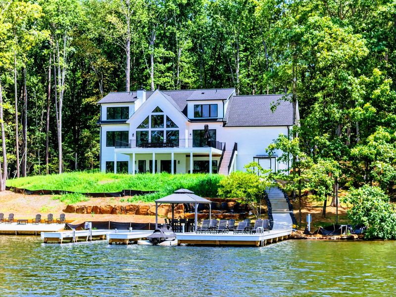 Waterfront - Side view from the water showing the dock and the home nestled among mature trees.