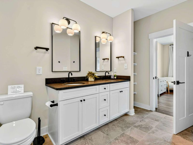 Primary Bathroom - Dual vanity with black fixtures and globe lights, view through to the bedroom.