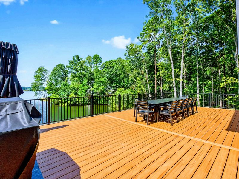 Main Deck - Dining table for ten on the composite deck with a grill and lake views through the trees.