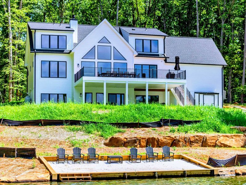 Rear Exterior - The modern A-frame with walls of glass rises above the sandy beach and waterfront.