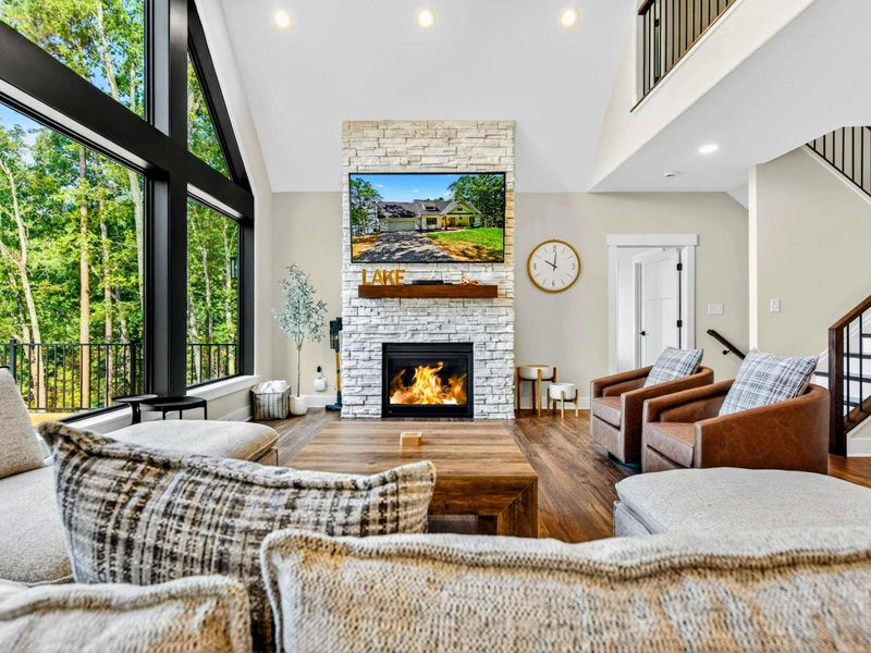 Great Room - Floor-to-ceiling A-frame windows frame lake views behind the stone fireplace and plush seating.