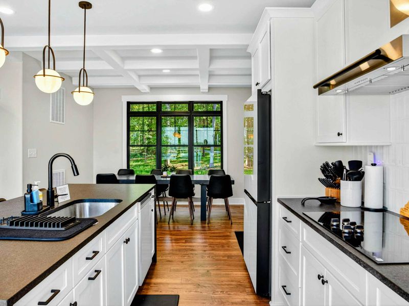 Kitchen - Galley view toward the dining nook with black mid-century chairs and a coffered ceiling.