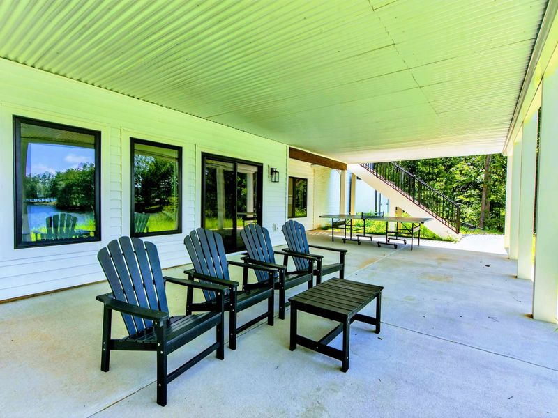 Covered Patio - Side angle showing the Adirondack seating area and staircase to the upper deck.