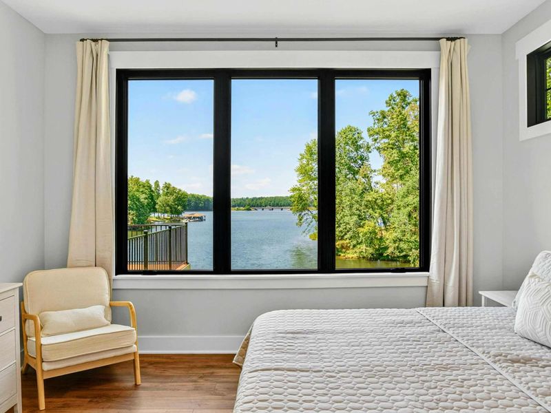 Primary Suite - Wake up to views of the lake and dock through oversized black-framed windows.