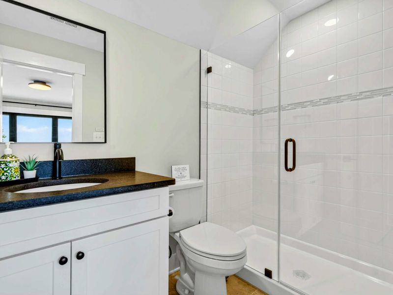 Bathroom 4 - Single vanity with glass-enclosed tub and shower combo in clean white tile.