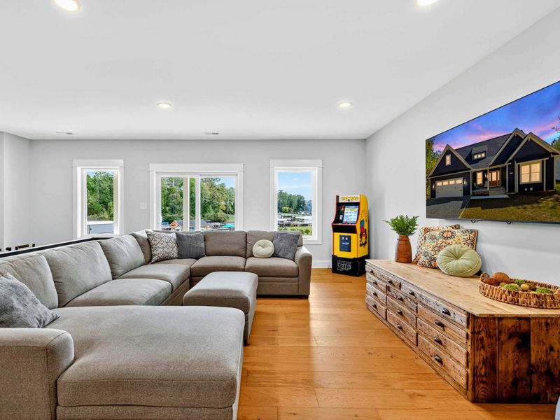 Rec Room TV Area - The sectional faces a large Smart TV with a rustic media console, an arcade cabinet, and bean bag chairs for extra seating.