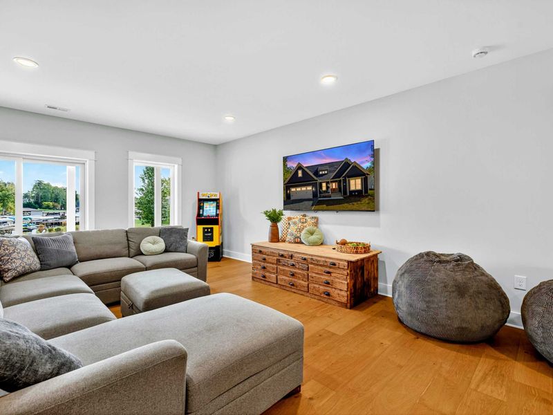 Rec Room Corner - Another angle of the Smart TV and sectional, with the arcade cabinet, lake views through the windows, and bean bags scattered around.
