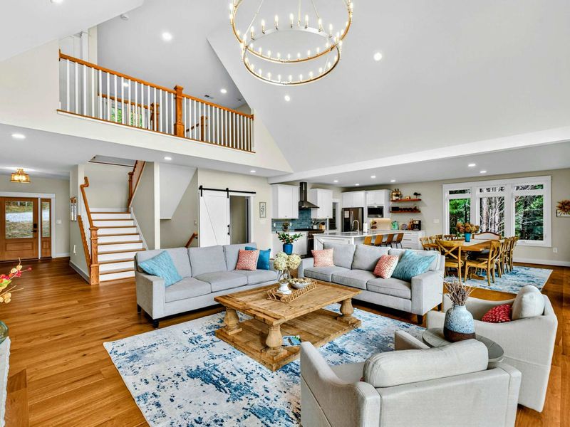 Great Room and Loft - The open living area with the upper loft railing, staircase, kitchen, dining, and barn door all visible from one vantage point.