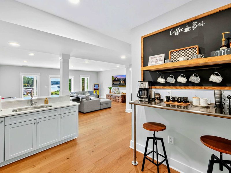 Our French country theme custom Coffee Bar with reclaimed wood shelves & stainless counter is fully stocked with an espresso machine & drip coffee, hanging mugs & syrups, all set against peaceful lake views - a real custom addition at Blueberry Bay!