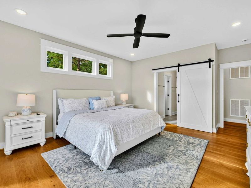 Primary Ensuite  - Sliding barn doors reveal a spa-like ensuite with double vanities, quartz countertops, a seated makeup area, glass-enclosed shower, and a spacious walk-in closet—bringing both luxury and convenience to your stay.