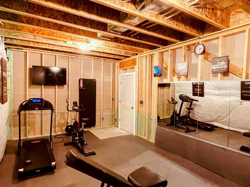 A well-equipped home gym with cardio machines, strength training equipment, large mirrors, and motivational artwork—perfect for maintaining your fitness routine.