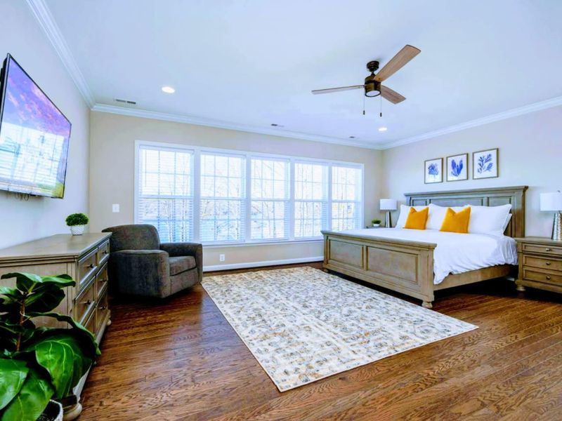 Primary Suite - King bed, wall-mounted TV, and a row of windows that catch the morning light off the lake.