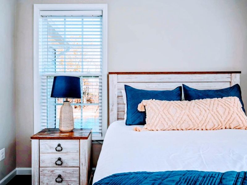 Bedside Detail - Soft layered linens, navy throw pillows, and a turned-leg nightstand: little details, big sleep-quality payoff.