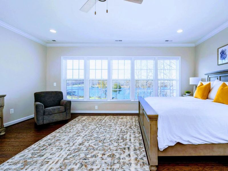 Primary Suite - King bed with the cove framed in the windows, plantation shutters, the room you'll come back to all week.