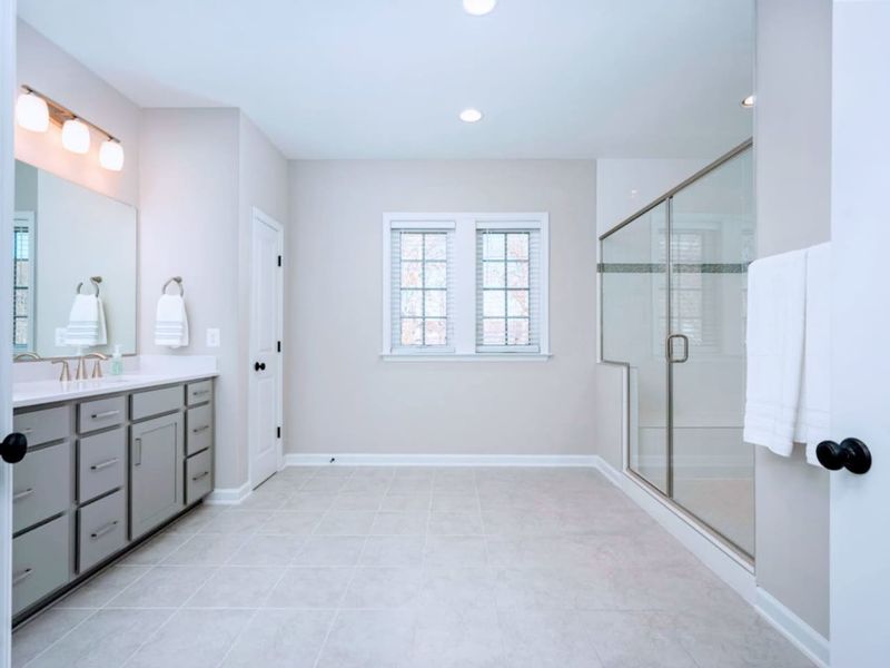 Primary Bath - Gray dual vanity, glass walk-in shower with a bench, and tile floor that keeps everything bright and easy.