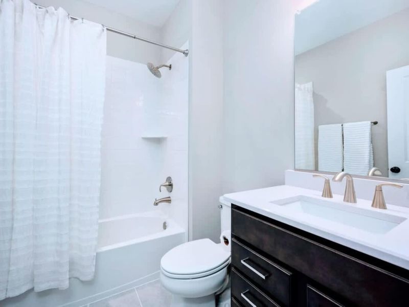 En Suite Bath - Full tub-shower combo, dark vanity, and a wide mirror that keeps the small space feeling bright.