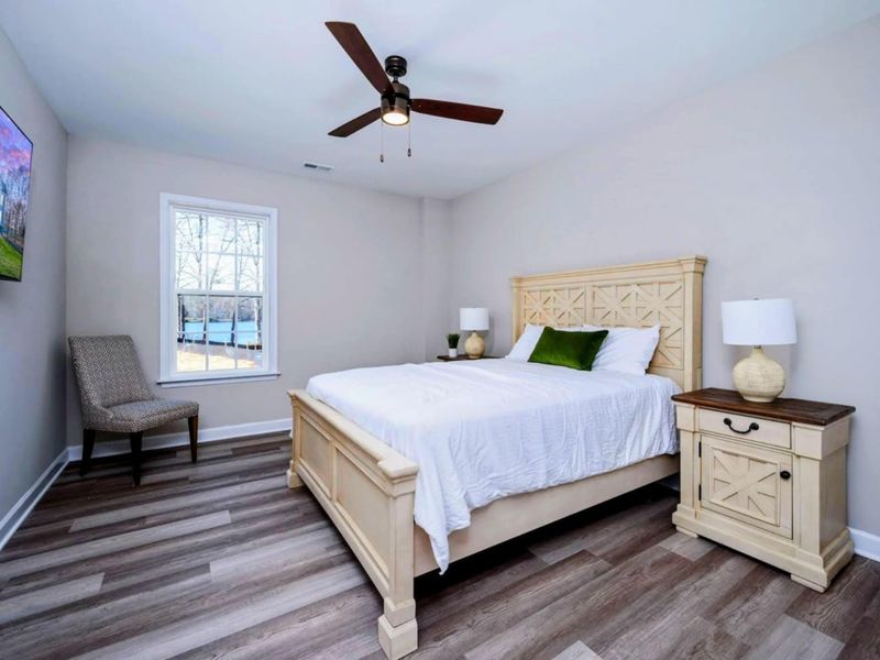 Lower Level Queen - Carved cream-wood bed, lake view through the window, and a private bath right next door.