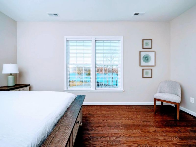 Upper Queen Suite - Sitting nook by the window, plantation shutters, and the lake visible through the slats first thing.