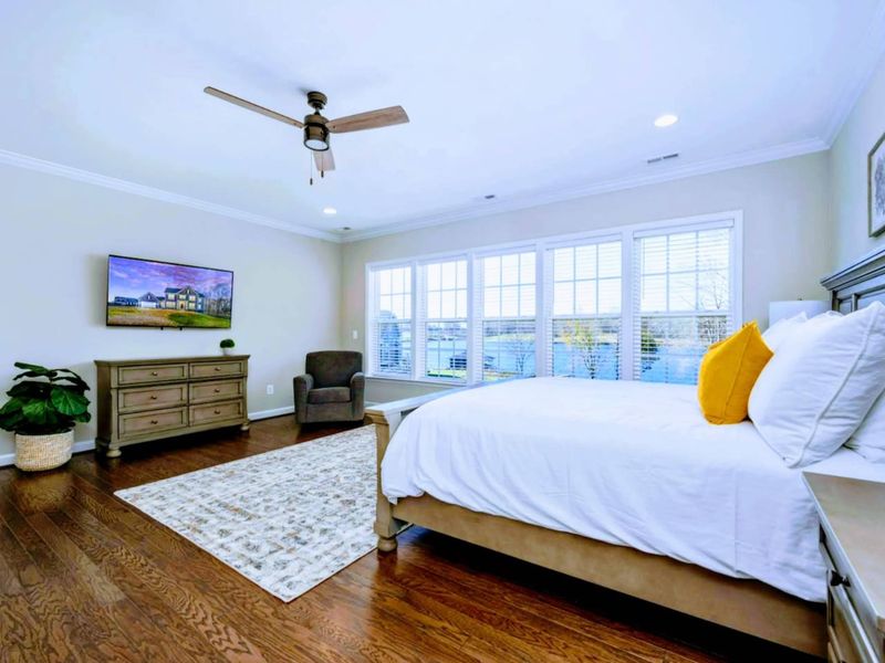 Primary Suite - Generous footprint with a sitting chair, dresser, and big windows that keep the lake in view.