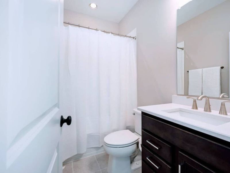 Guest Bath - Tub-shower combo, dark vanity, and quartz counter: an everyday bath that still feels like a proper guest space.