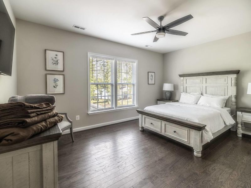 Rest in comfort in this serene bedroom, complete with a plush queen bed, ceiling fan, and abundant natural light for a peaceful retreat