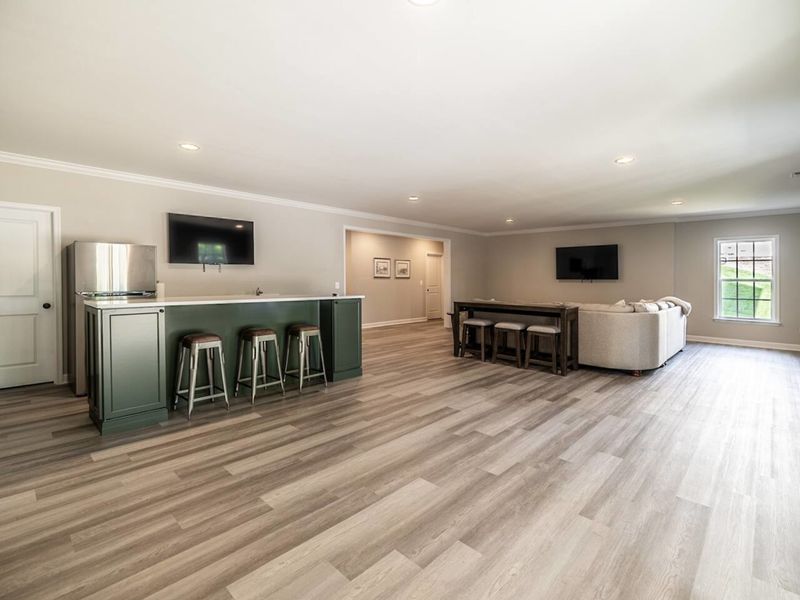 Unwind in style in the lower level family room of this lakeside getaway, complete with a comfortable couch, an entertainment-ready TV, a versatile island perfect for dining or socializing, and an additional fridge for added convenience.