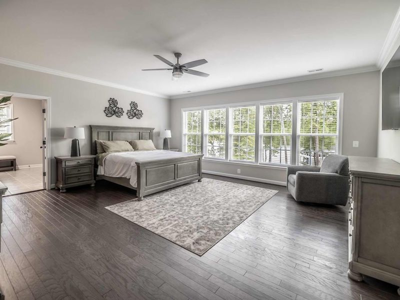 Relax in the spacious Primary Bedroom with luxurious furnishings, modern amenities, and a serene view of the lush surroundings
