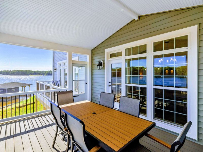Screened-in porch with dining area and panoramic lake views, perfect for enjoying meals outdoors