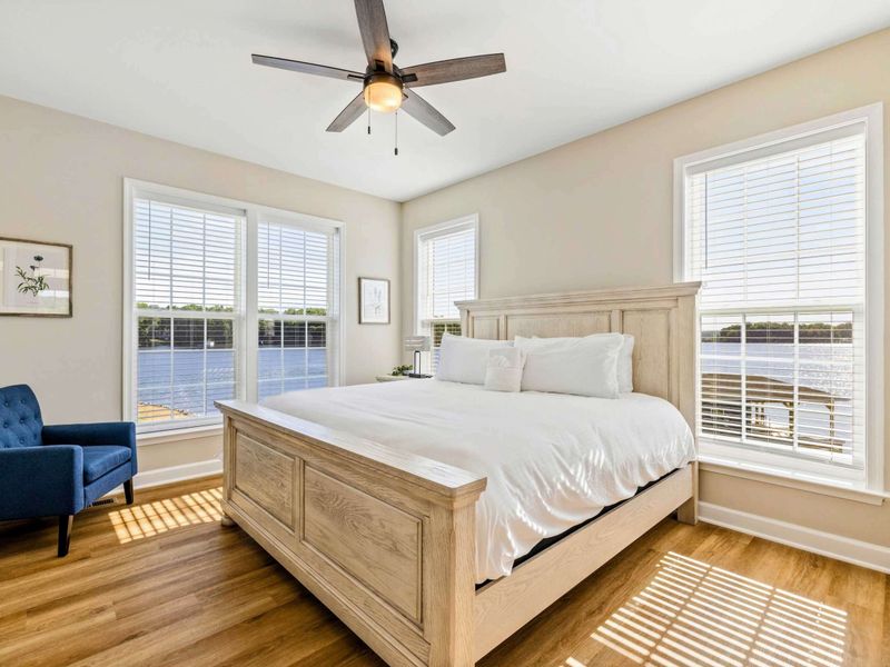 Bright and airy bedroom with a king-size bed, ceiling fan, and beautiful lake views