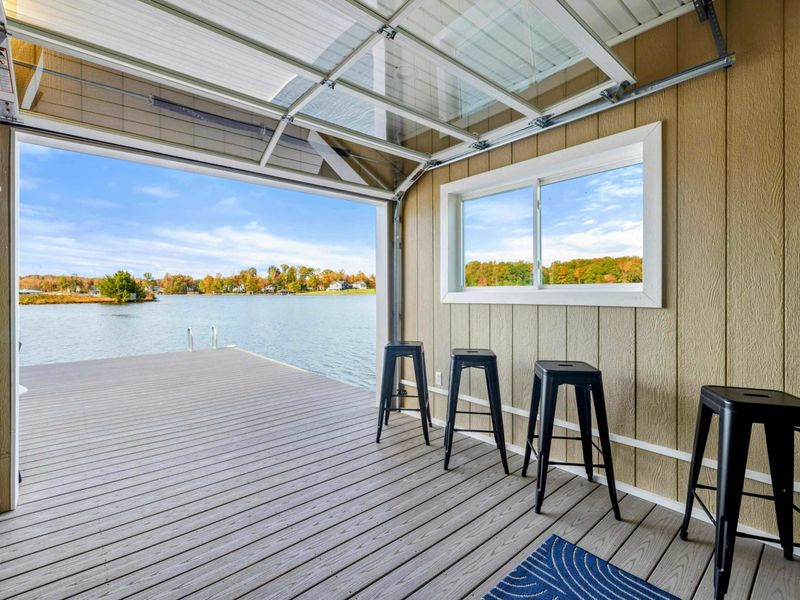A serene lakeside space with a bar area and a fully retractable glass door that opens directly onto a spacious dock