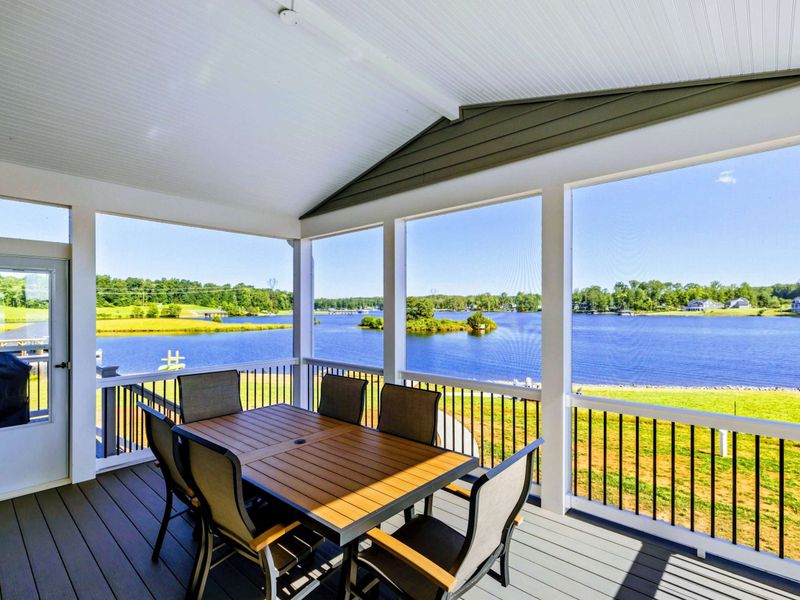 Screened-in porch with dining area and panoramic lake views, perfect for enjoying meals outdoors