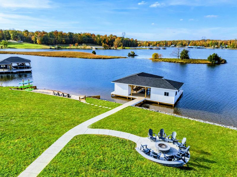 A scenic lakeside property featuring a cozy fire pit area, a private boathouse, and breathtaking water views