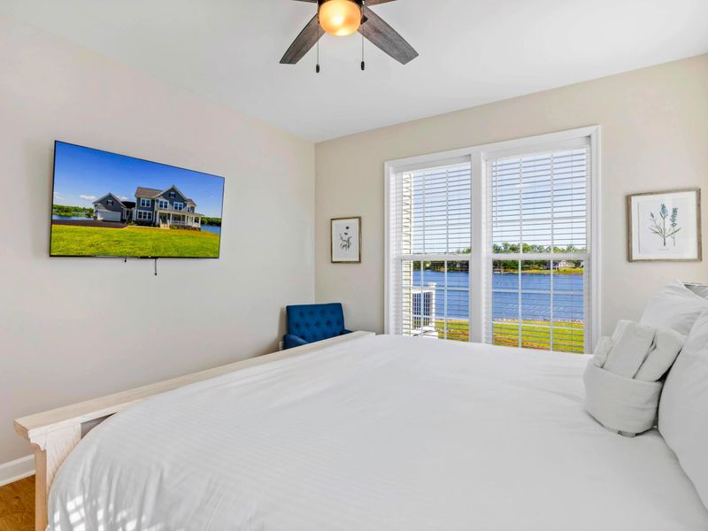 Bedroom with a king-size bed, wall-mounted TV, and stunning lake views through large windows