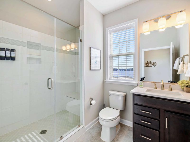 Modern bathroom with a glass-enclosed shower, vanity, and a window offering natural light and lake views