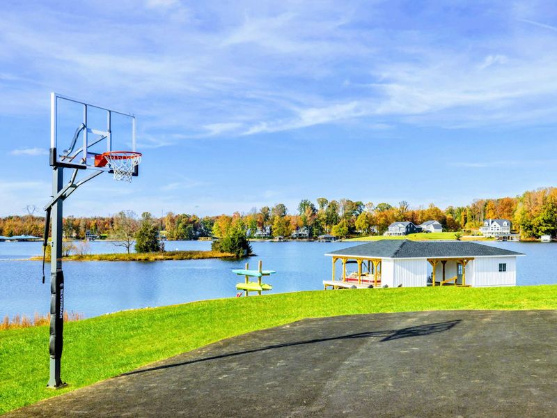 A lakefront property with a basketball court and a boathouse, offering both recreational fun and scenic water views