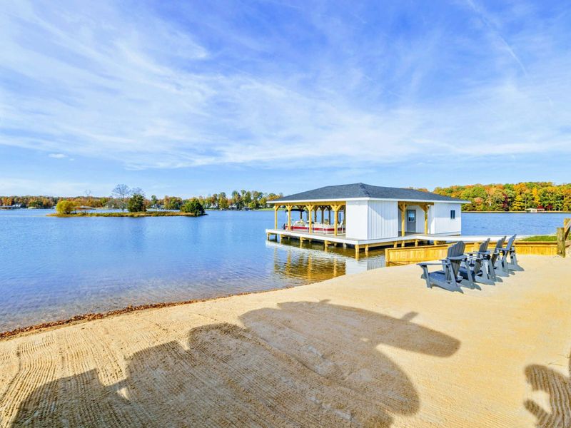 A sandy lakeside area with Adirondack chairs and a charming boathouse, perfect for relaxing and enjoying the water views
