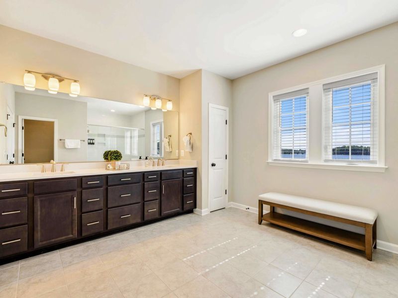 Modern en-suite bathroom with a large mirror, double vanity, and elegant lighting