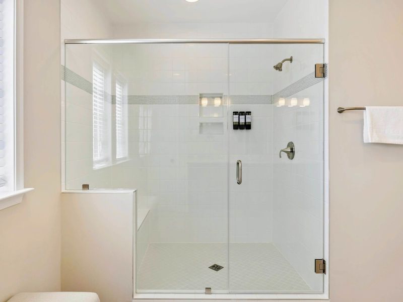 Spacious glass-enclosed shower with modern fixtures and natural light