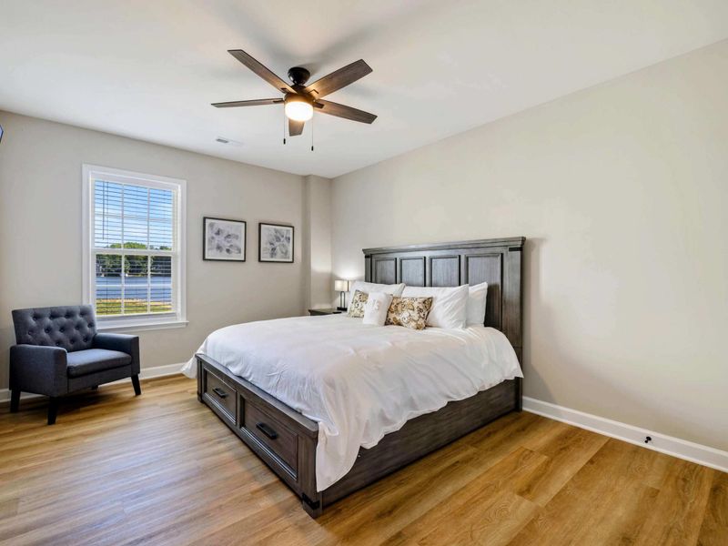 Spacious bedroom with a king-size bed, ceiling fan, and wall-mounted TV